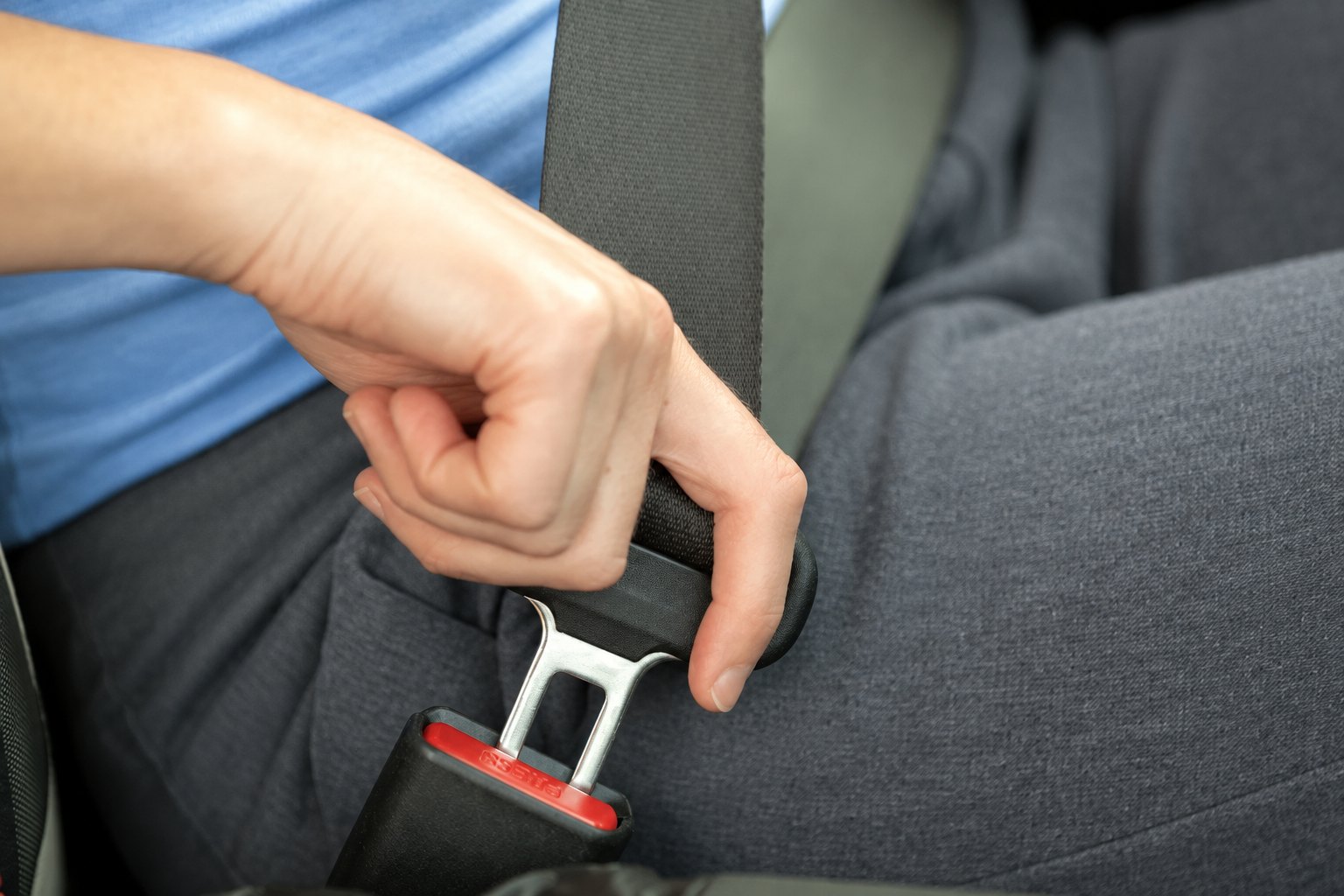 Close-up of a person fastening a car seatbelt.