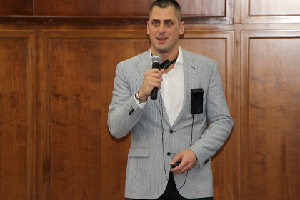 mike in light grey suit jacket holding microphone